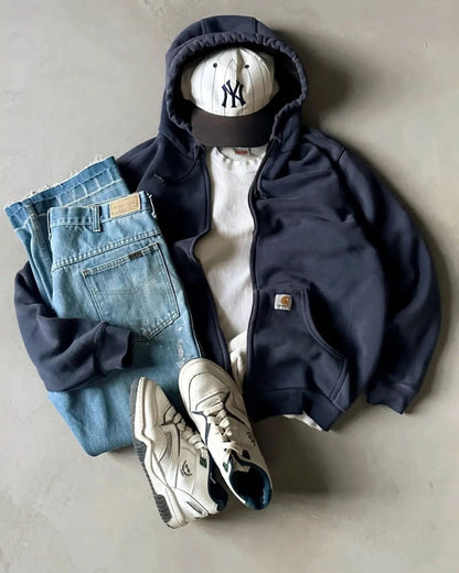Outfit vintage steso a terra: felpa blu con cappuccio, maglietta color crema e jeans chiari